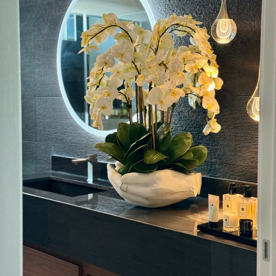 Orquídeas Phalaenopsis blancas en macetero escultura de manos abiertas